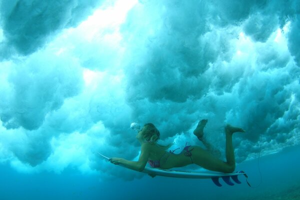 Chica en una tabla de surf bajo el agua