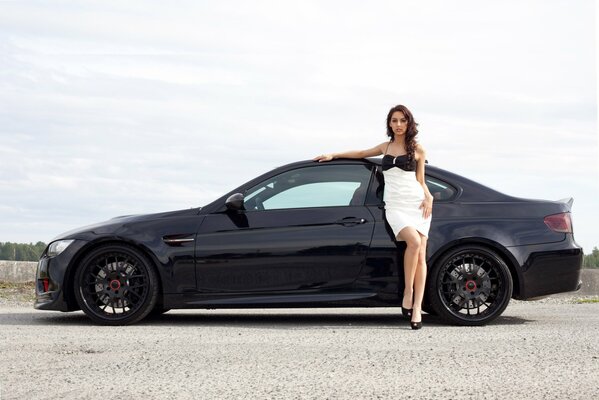 Chica en un hermoso vestido al lado de un negro BMW