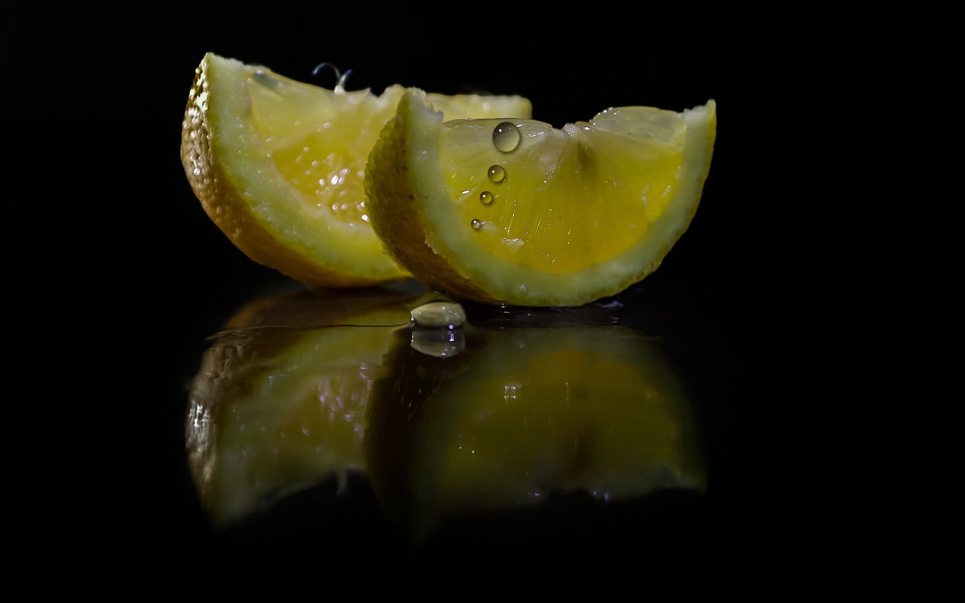 lemon segments juice drops dark background reflection