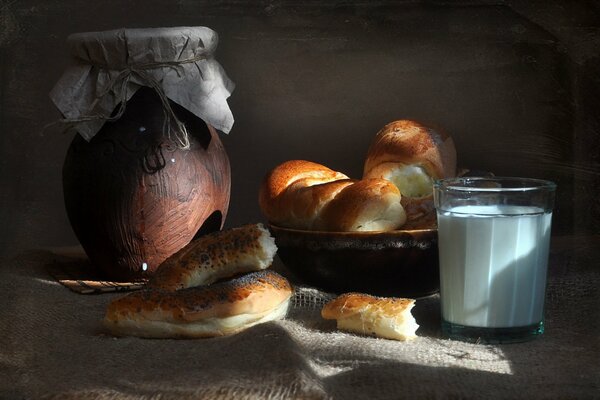 A shadow falls on the buns with a glass of milk