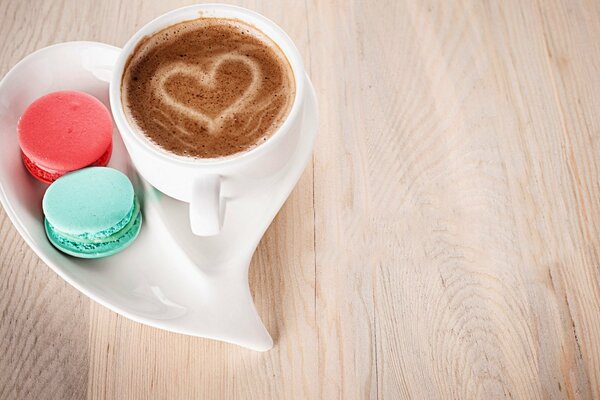 Une tasse de café avec un coeur sur la mousse et deux gâteaux