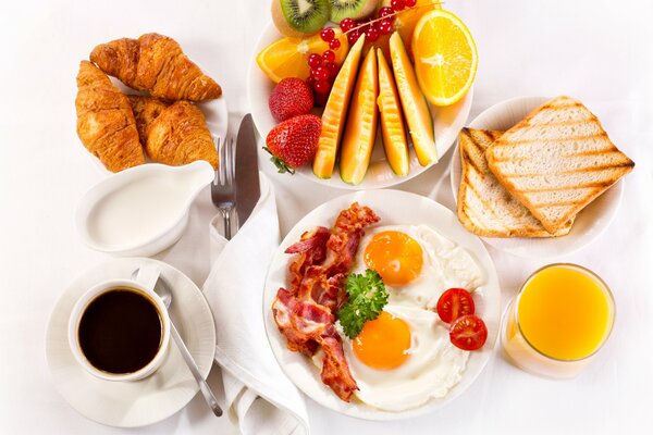 Petit déjeuner servi sur la table avec des croissants café brouillés avec du bacon et des fruits