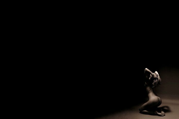 Naga dziewczyna trzymająca się za głowę na ciemnym tle