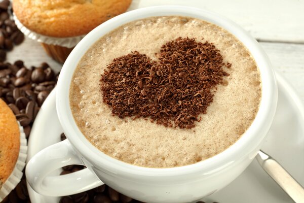 Tasse Kaffee mit Schokoladenherz und Muffins