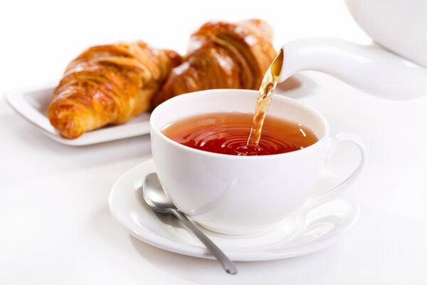 Une tasse de thé avec un croissant pour le petit déjeuner