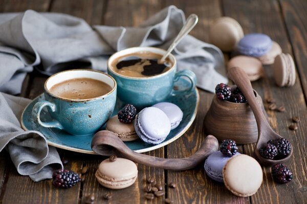 Tazas de café azul y postre de macarrones con moras