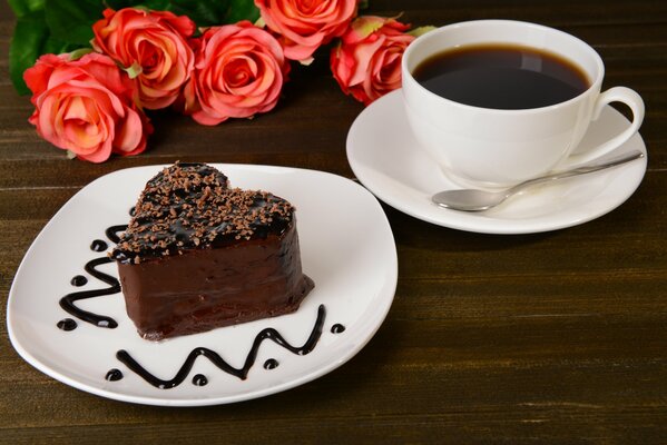 Roses. A cup of coffee and a chocolate cake in the shape of a heart