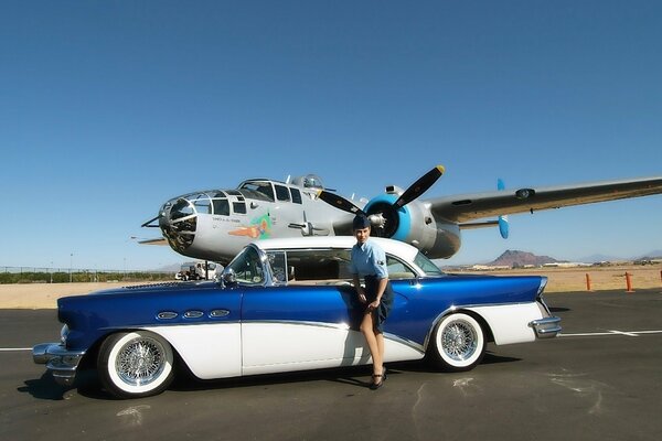 A girl with a retro car on the background of an airplane