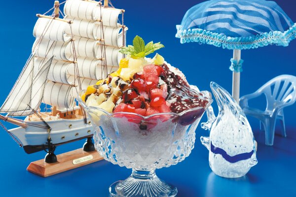 Dessert and next to it a model of a boat and accessories in the form of an umbrella and a chair