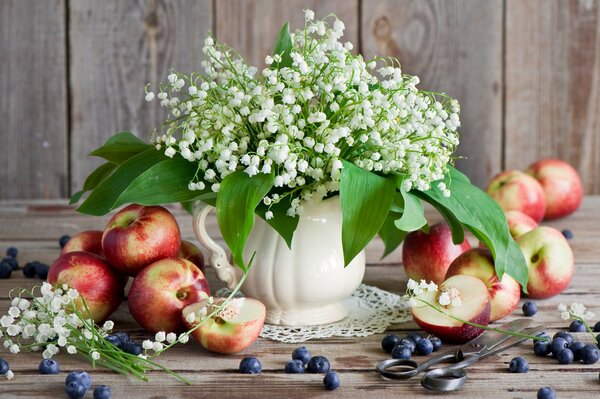 Tiernos lirios del valle en el fondo de manzanas y arándanos