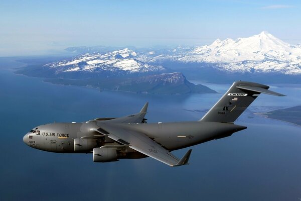 Black Boeing C-17 flies near the mountains