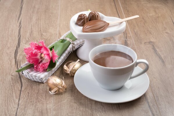 Kubek aromatycznej kawy ze słodyczami i kwiatem