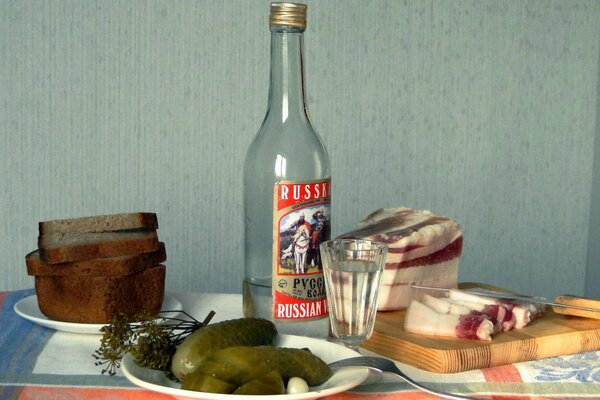 Русская водка, огурцы и сало на столе