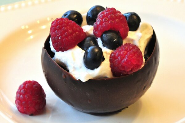 Dessert in einer Schokoladenschale mit Sahne aus Himbeeren und Blaubeeren