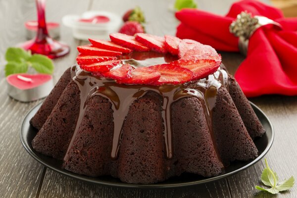 Cupcake decorated with icing and strawberries on a background of napkins and candles