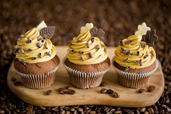 Tre cupcakes su una tavola con crema e cioccolato