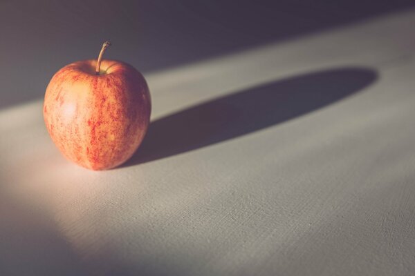 Einsamer roter Apfel auf einer weißen Tischdecke