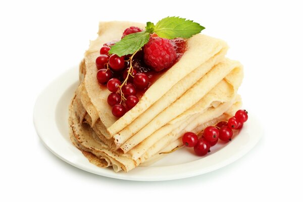 Pancakes on a plate with currants, raspberries and mint