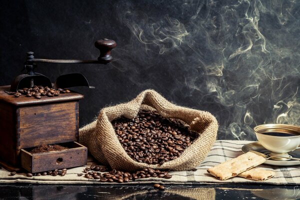 Sacchetto di caffè in grani sul tavolo accanto alla tazza e al macinacaffè