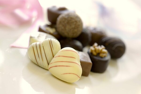 Caramelle al cioccolato bianco a forma di cuore su uno sfondo di caramelle al cioccolato al latte