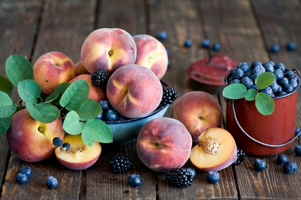 Reife Pfirsiche und ein Eimer mit Blaubeeren