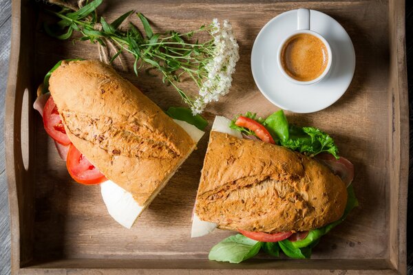 Sandwich with coffee and flowers in a wooden tray