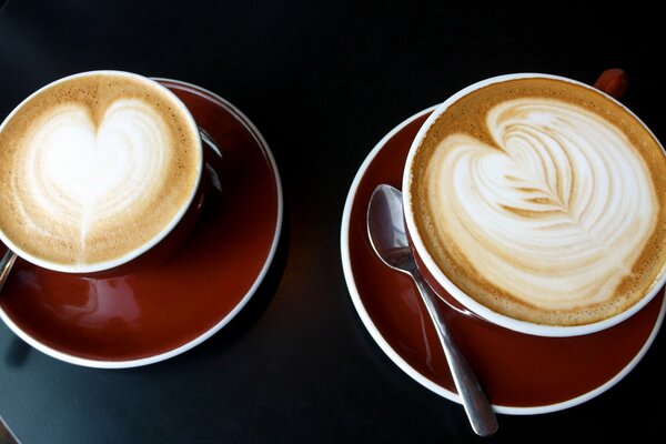 Two cups of coffee with a pattern on the foam