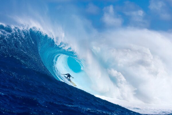A surfer passes under a big wave