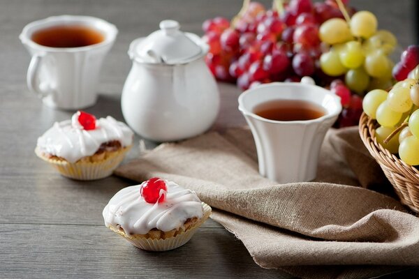 Té con pasteles y uvas en la mesa