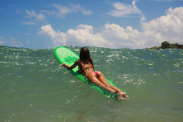 Das Mädchen auf dem Surfbrett liegt im Badeanzug