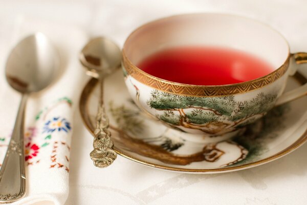 A cup of tea with a saucer and teaspoons