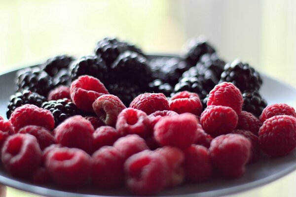 Tapete mit frischen Himbeeren und Brombeeren auf einem Teller