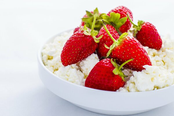 Fresa con requesón en un plato sobre un fondo blanco