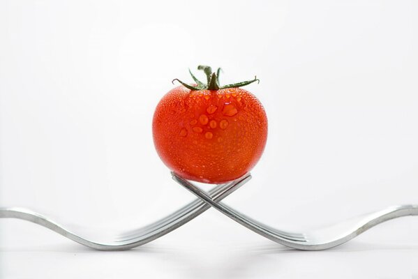 Fresh and juicy tomato balances on forks