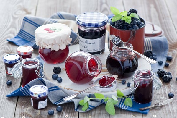 Jars of jam next to blueberries and blackberries