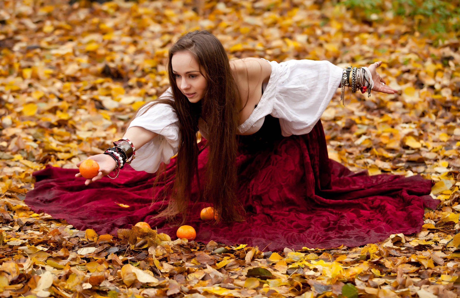 fille en robe mandarines assis feuillage automne