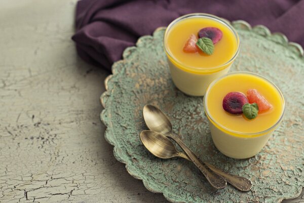 Two cocktails on a tray with fruit and a leaf