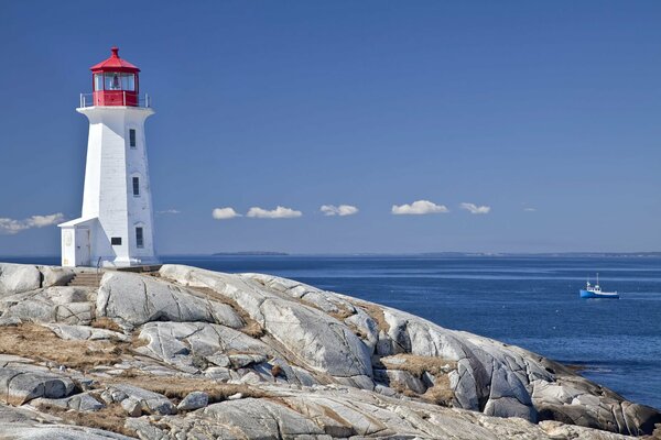 Lighthouse and stones on the background of the sky and the sea