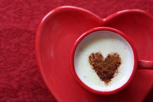 A cup of coffee with milk decorated with a cocoa heart