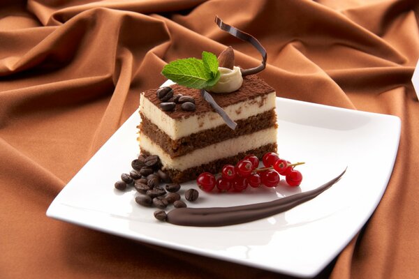 Chocolate cake on a plate with red currants