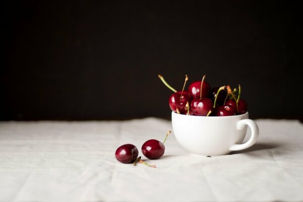 Cherries on the table in a white cup