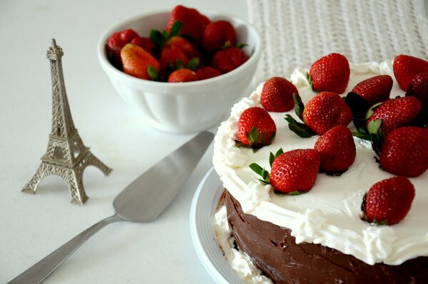 Chocolate cake with strawberries on the table with a statuette of the Eiffel Tower next to it