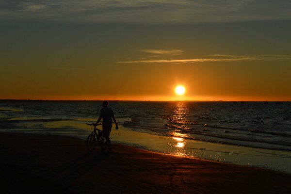 Un hombre paseando por la playa en medio de una puesta de sol