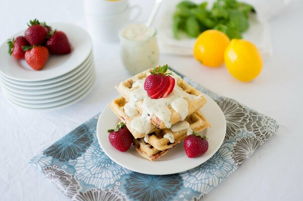 Waffles with cream and fresh strawberries and lemon