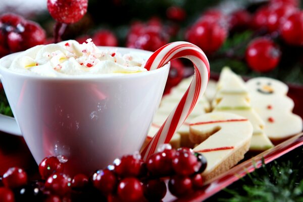 A cup of hot drink with lollipops in the form of a cane