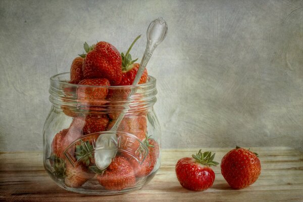 Barattolo di vetro con cucchiaio insieme alle fragole