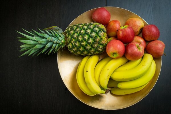 Jabłko banan i ananas leżą na talerzu