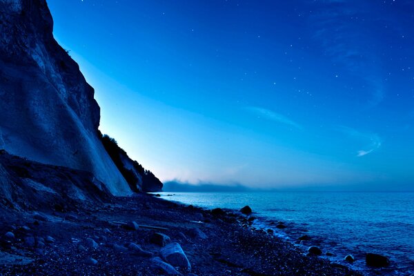 Moon in the night sky over water and mountain