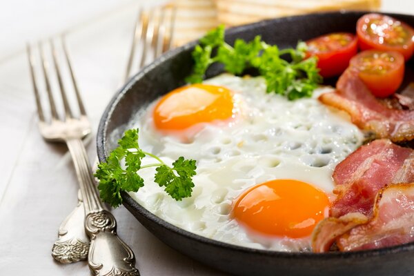 Delicioso Desayuno de dos huevos y tocino con tomates