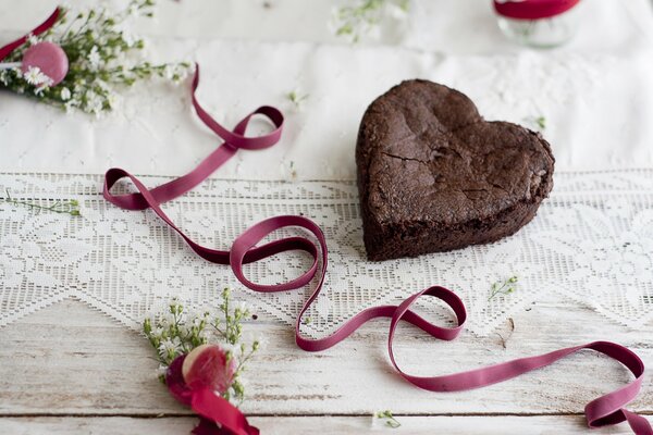 Corazón de pastel de chocolate y cinta rosa